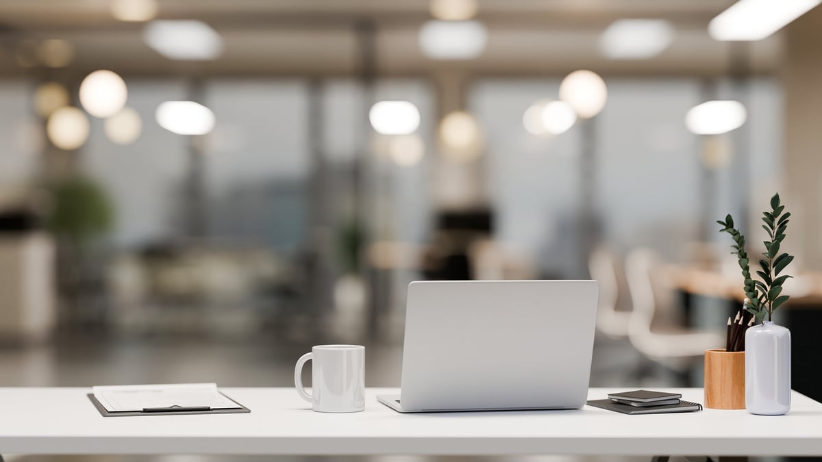 Minimalist office desk in co-working office room with laptop and copy space on white table 3D render.